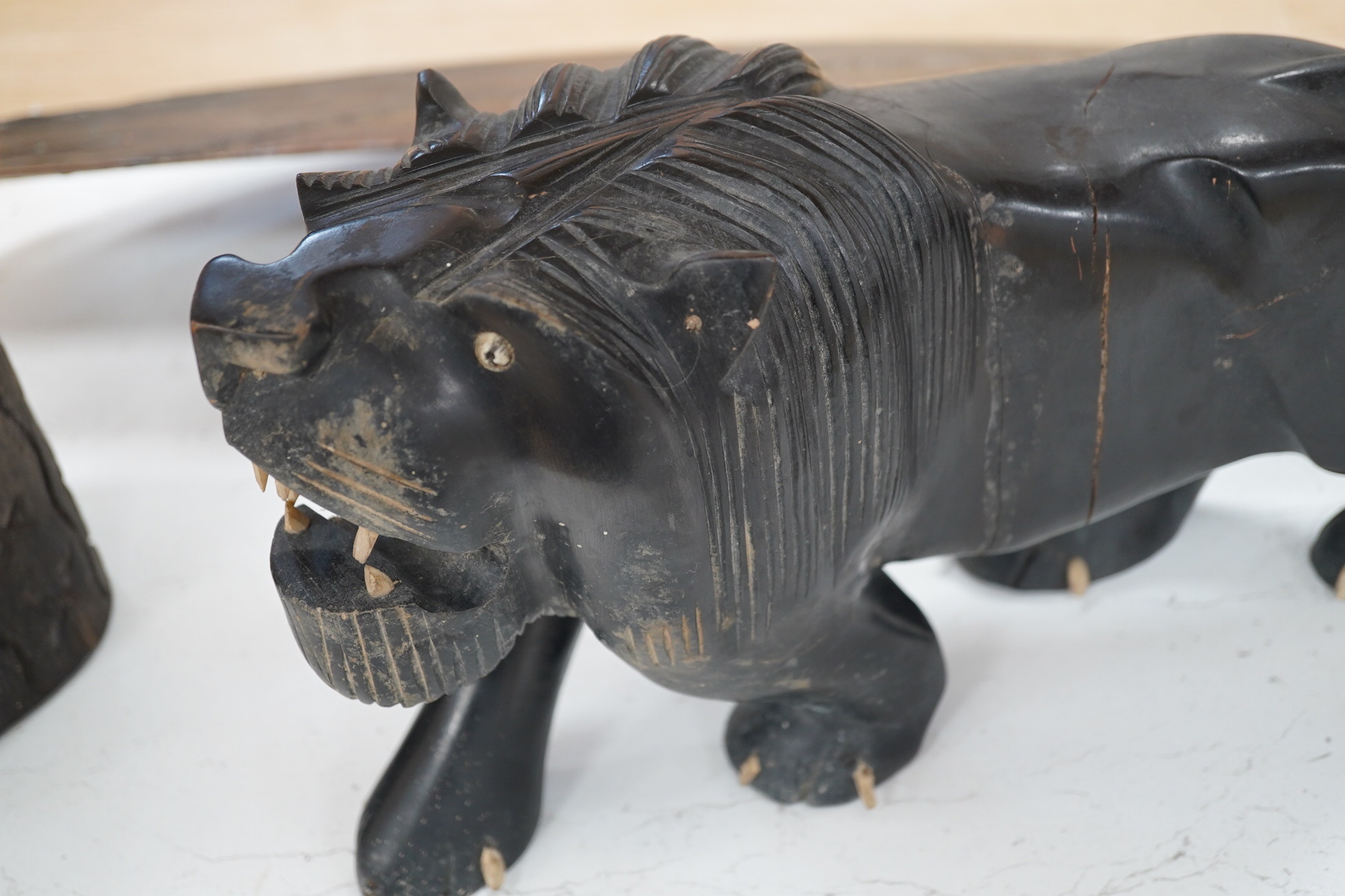 An African hardwood carving of a bust, 41cm high and an ebony Indian carving of a lion, 35cm long, (2). Condition - fair